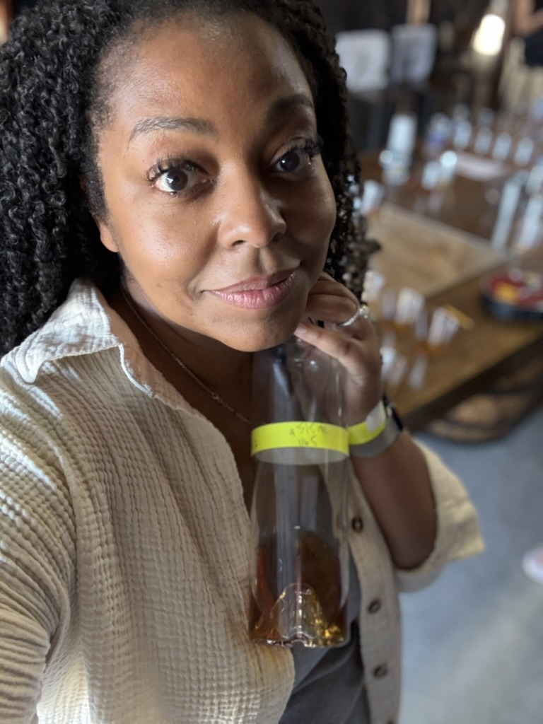 Kim raising a cocktail in a barrel room