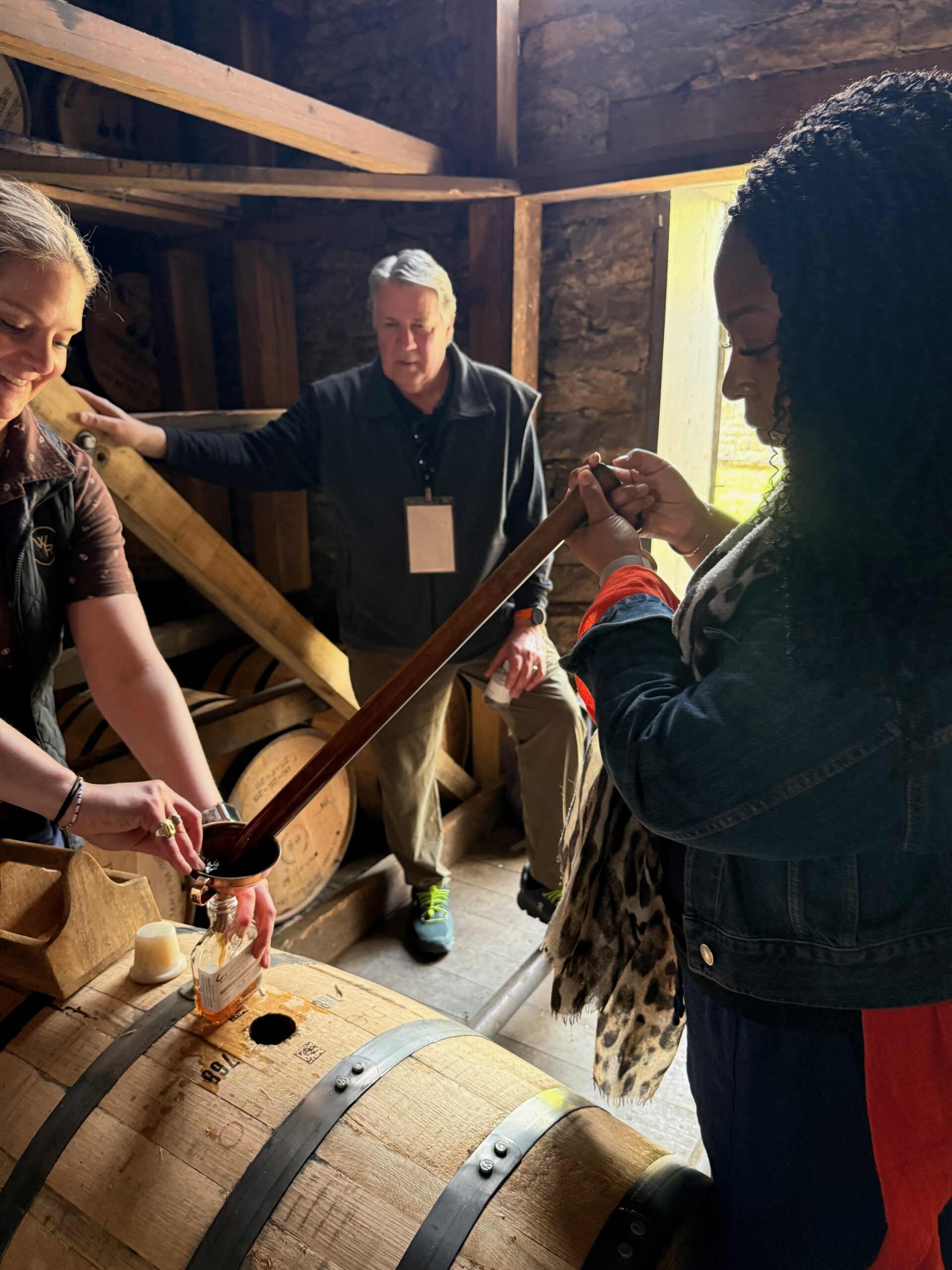 Kim pouring a tasting at a barrel room table